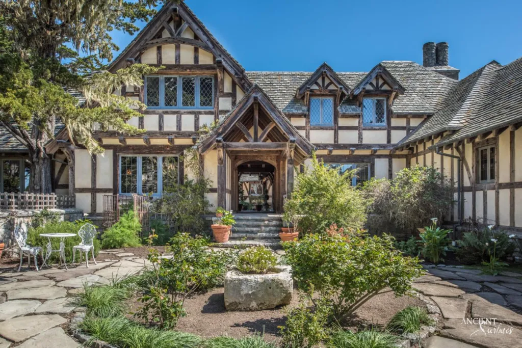 Half timbered stone villa exterior with steep tiled gables, leaded glass windows and a courtyard garden