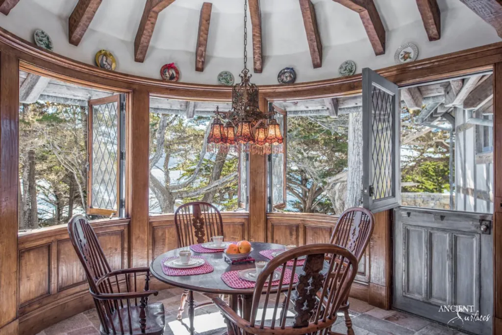 Round breakfast nook with leaded glass windows and hand painted plates adjoining the stone floored kitchen