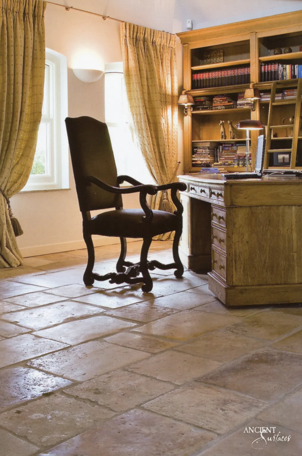 Large format antique limestone floor pavers beneath a wingback chair and writing desk in a study