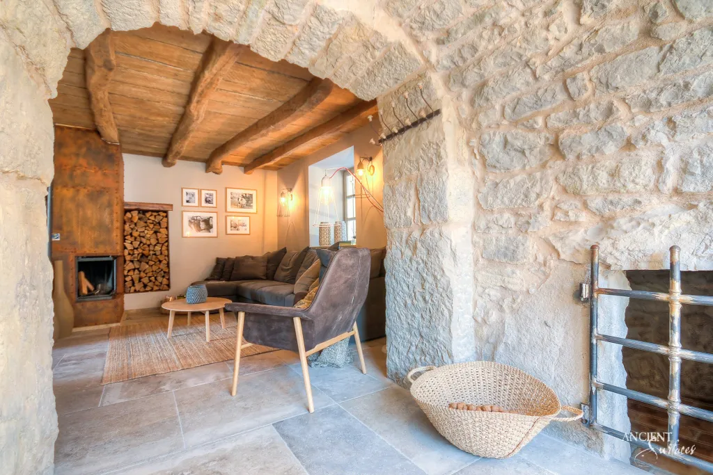 Rubble stone archway opening onto a living room clad entirely in reclaimed stone